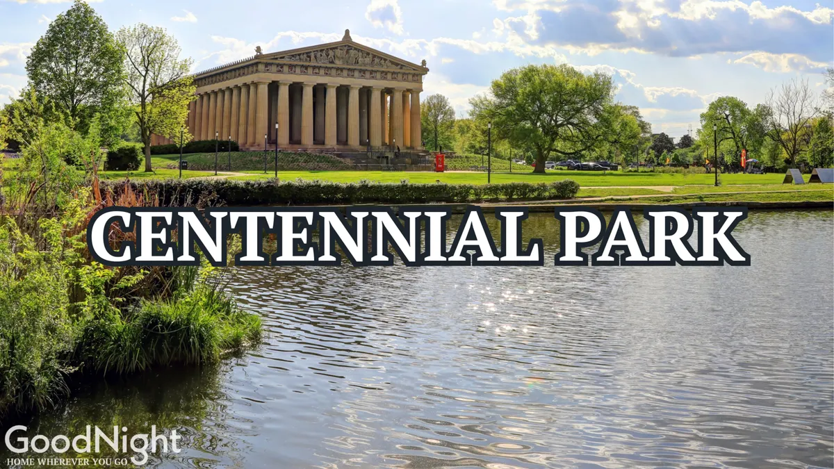 A peaceful scene of the Parthenon replica in Centennial Park, reflected in a calm body of water and surrounded by lush greenery. The park-like setting invites walks, picnics, and family activities.