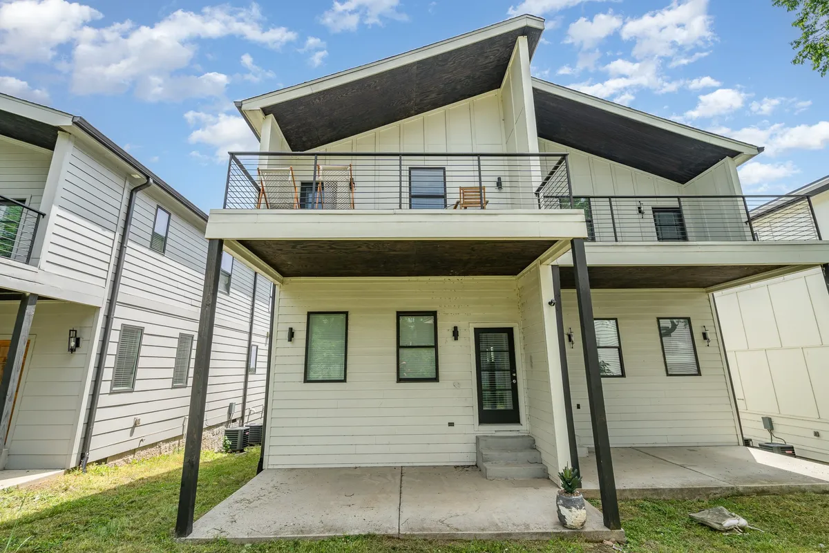 An inviting balcony and front entrance framed by attractive landscaping and large windows, suggesting spaces for outdoor relaxation and small group gatherings. The image has a welcoming vibe, making it ideal for socializing and unwinding.