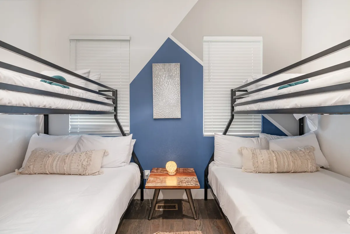 A cozy bunk bed room with decorative wall art and a small wooden table, evoking a youthful, playful atmosphere. The arrangement is perfect for group travelers or families looking to bond and create memories together.