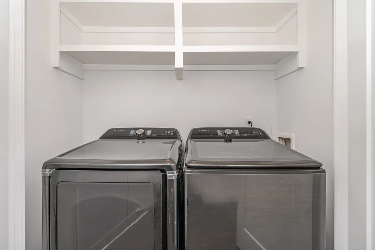 A dedicated laundry room with a washer, dryer, and shelves for organizing laundry essentials. The setup is practical and efficient, highlighting convenience for guests during their stay.